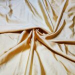 Cream-colored satin fabric with soft folds.