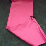 Bright pink fabric sleeve with a drawstring closure on a dark surface.