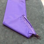 Purple fabric piece with a zipper on a gray surface.