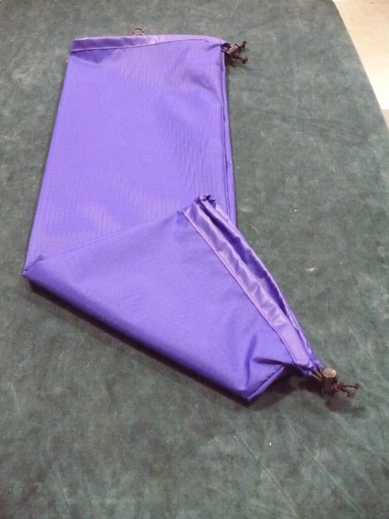 Purple fabric piece with a zipper on a gray surface