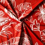 Red fabric with white tropical leaf patterns.